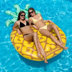 two women laying on an inflatable banana float at the edge of a pool