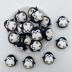 a white plate topped with lots of black and white penguin magnets on top of a table