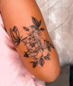 a woman's arm with flowers and butterflies tattoo on the left side of her arm