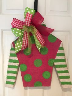 a red and green door hanger with polka dots on it's side, attached to a white door