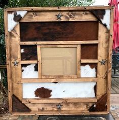 an old wooden frame with cow hide and stars on the side, sitting on a patio