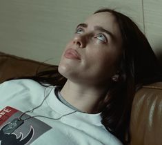 a woman sitting on top of a couch wearing a batman t - shirt and necklace