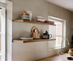 the shelves in the kitchen are filled with dishes and cups, along with bowls on them