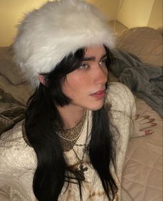 a woman with long black hair wearing a white fur hat on top of her head