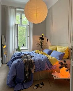 a bed room with a neatly made bed next to a large window and a lamp