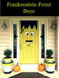 two planters with plants in front of a yellow door that has a monster face on it