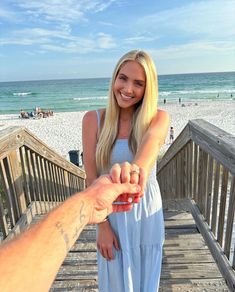 a woman holding the hand of a man on a boardwalk