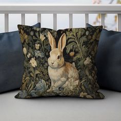 a decorative pillow with a rabbit on it's side sitting on a porch bench