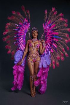 an image of a woman in pink and purple costume with feathers on her head, posing for the camera