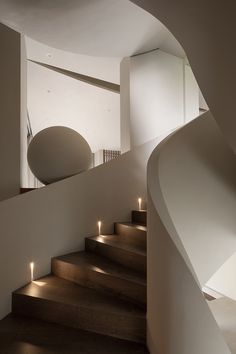 some lights are lit up on the stairs in this modern house with white walls and wood flooring