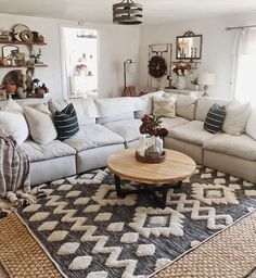 a living room filled with lots of white couches and pillows on top of a rug