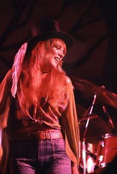 a woman with long red hair wearing a hat and holding a microphone in her hand