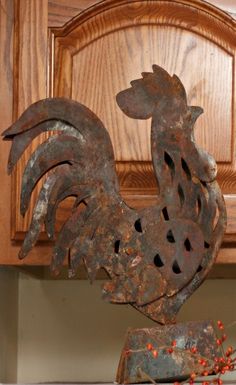 a metal rooster on top of a wooden cabinet