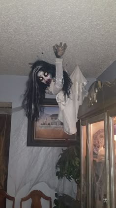 a creepy doll hanging from the ceiling above a dresser