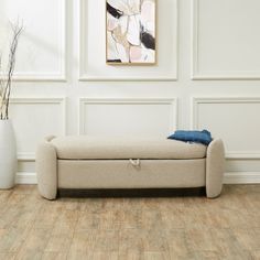 a white couch sitting on top of a wooden floor next to a vase with flowers