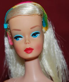 a doll with blonde hair and blue eyes wearing a colorful headband on her head