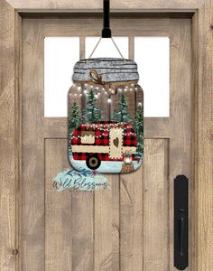 a mason jar with a christmas scene on it hanging from the side of a wooden door