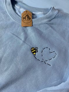 a blue shirt with a bee embroidered on it