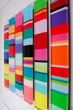 an art piece is hanging on the wall in front of a white background with multicolored squares