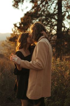 a man and woman are kissing in the woods