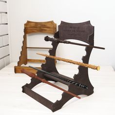 three different types of swords on display in front of a white brick wall and two wooden chairs