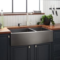 a kitchen with black cabinets and stainless steel sink, counter tops, and wooden counters