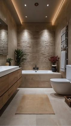 a bathroom with a tub, toilet and sink in the middle of it is illuminated by recessed lighting