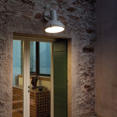 an open door leading into a room with a lamp on the wall and windows in it