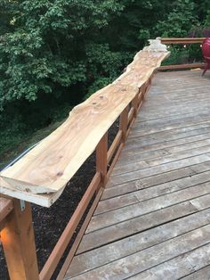 a wooden bench sitting on top of a wooden deck next to a lush green forest