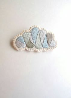 an embroidered brooch with three different colored shapes on the back and sides, sitting on a white surface