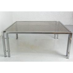 a glass table with metal legs on a white floor