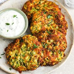 three fritters on a plate with a small bowl of ranch dressing