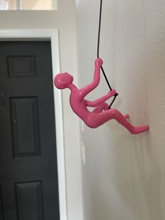 a pink figure hanging from the side of a wall