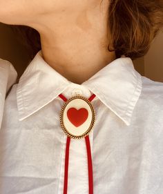 AVAILABLE IN PINK HERE: https://fatcatfancy.etsy.com/listing/1603089136 * * Introducing the Lovely Red Heart bolo tie! It features a 30mmx40mm heart cameo set in your choice of silver or bronze rope bezel with a roped edge. The pendant's back includes a gold or silver-plated adjustment mechanism for easy on-and-off and personalized pendant placement. Suspended by sturdy nylon paracord, the pendant is complemented by  gold or silver plated cord tips.  * * The cord length of this necklace spans approximately 36 inches, providing a balanced drape of 18 inches on each side when worn. Should the slide require a tighter or looser fit, a simple adjustment using pliers on the back will securely fasten or release the pendant, enabling smooth sliding along the cord. For those seeking a cord change o Bolo Ties, Tie Shop, Personalized Pendant, Cowboy Western, Tie Accessories, Suit And Tie, Western Cowboy, Red Heart