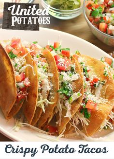 a white plate topped with tacos covered in cheese and veggie toppings