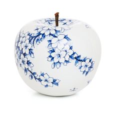 an apple with blue and white flowers painted on it's side, in front of a white background