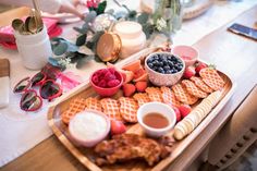 a wooden tray topped with waffles and fruit