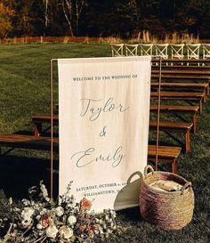 a welcome sign sitting on top of a grass covered field next to a wooden bench