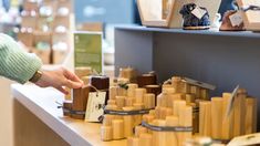 a person standing in front of a counter with wooden items on top of it and one hand reaching for something