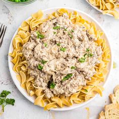 a white plate topped with pasta covered in meat sauce and garnished with parsley