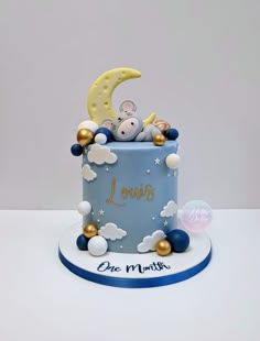 a blue cake with white and gold decorations on it's side, topped by a moon