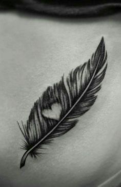 a black and white photo of a woman's stomach with a heart shaped feather on it