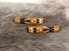 two beaded hair clips sitting on top of a furry surface