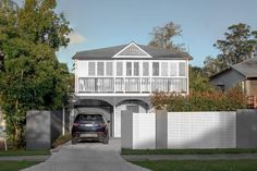 a car is parked in front of a house with a white picket fence and gate