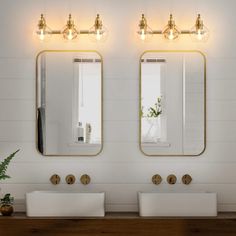 there are two sinks in the bathroom with mirrors above them and lights on the wall