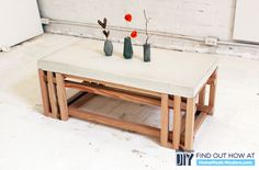 three vases with flowers sit on top of a coffee table in front of a white brick wall