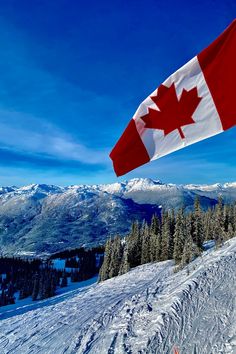 the canadian flag is flying high above the snow covered slopes in front of some mountains