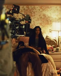 a woman sitting on top of a bed next to a camera