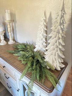 two white christmas trees sitting on top of a dresser