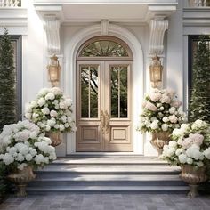 two large vases filled with white flowers sitting in front of a door to a house